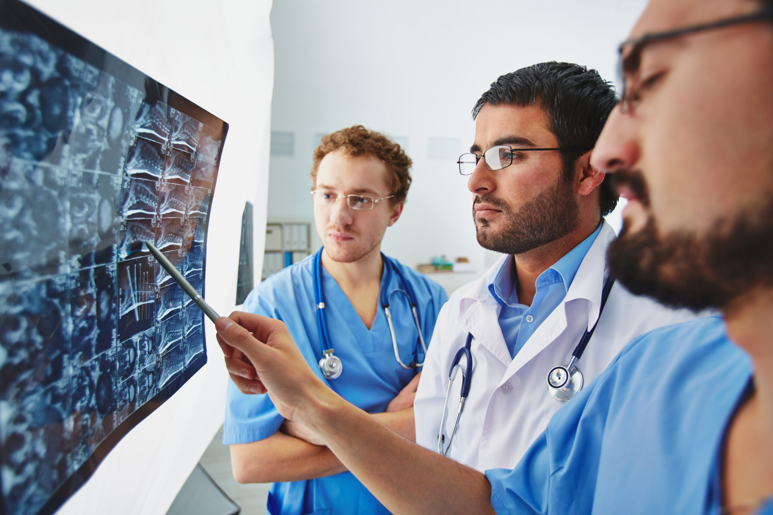 Jeunes médecins masculins regardant attentivement une radiographie et en discutant
